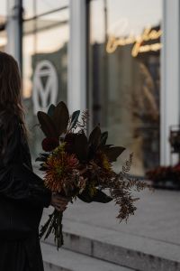 Kaboompics - Woman Holding an Autumn Bouquet Beside Glass Shopfront