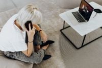 Kaboompics - Woman Taking a Phone Call from the Sofa with Laptop Nearby