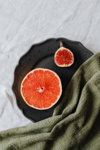 Kaboompics - Fresh Fig and Grapefruit on a Black Plate with Green Linen, Citrus Fruit Editorial