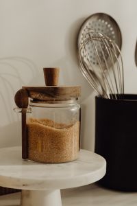 Kaboompics - Close-Up of Brown Sugar in a Glass Jar on a White Marble Stand, Kitchen Utensils Background