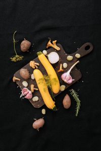 Kaboompics - Yellow Vegetables, Garlic and Herbs on a Dark Cutting Board