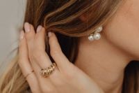 Kaboompics - Woman Adjusting Pearl Earring Wearing Gold Ring