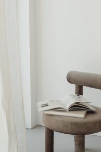Kaboompics - Minimalist Armchair with Open Book and Blank Wall Copy Space