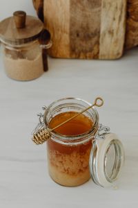 Kaboompics - Overhead Honey Jar and Wooden Dipper with Pantry Ingredients in the Background