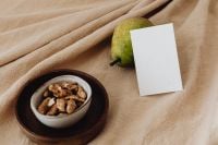 Kaboompics - Pear and Blank Business Card with Walnuts in a Ceramic Bowl on Dark Wood