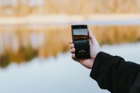 Kaboompics - Hand Holding a Smartphone to Photograph a Quiet Winter Lakeshore