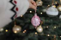 Kaboompics - Pink Christmas Ornament Held against Blurred Tree Lights