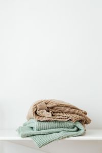 Kaboompics - Folded Sweaters on a White Shelf With Copy Space