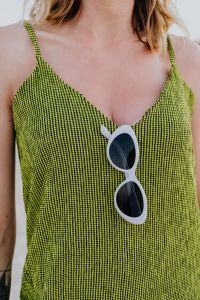 Kaboompics - A woman in a green dress on the beach with white sunglasses