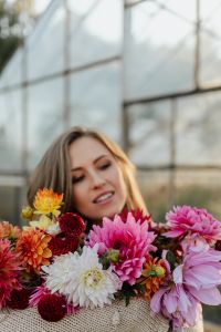 Kaboompics - Woman With Dahlia Bouquet And Glass Greenhouse Backdrop