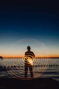Kaboompics - Light painting. The man waving fairy lights at the sea at sunset.