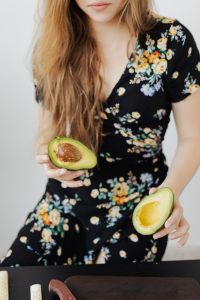 Kaboompics - Woman Holding Fresh Avocado Halves in a Floral Dress