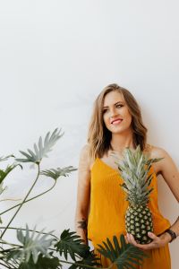 Kaboompics - Woman in Mustard Yellow Top Holding a Pineapple against a White Studio Wall