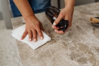 Kaboompics - Woman Spraying and Wiping a Marble Coffee Table