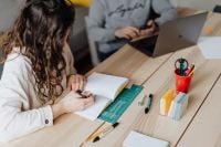 Kaboompics - Woman Writing at Desk with Man Using Laptop