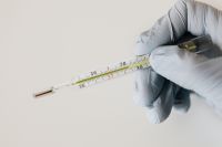 Kaboompics - Gloved Hand Checking a Glass Medical Thermometer, Close-Up Fever Care Detail