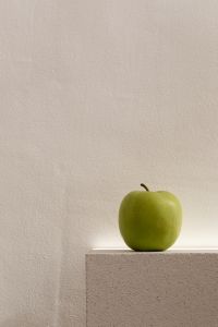 Kaboompics - Green Apple on a Low Stone Ledge Against a Textured Neutral Wall, Vertical Copy Space