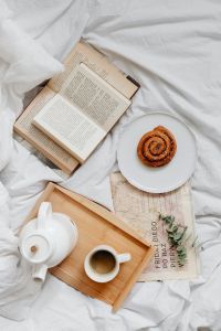 Cozy Breakfast in Bed with Coffee, Books, Croissants and Cinnamon Rolls