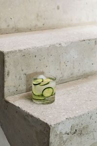Kaboompics - Cucumber and Lime Detox Water with Ice on Textured Concrete Steps, Vertical Background with Generous Copy Space
