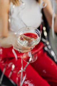 Kaboompics - Woman's Hand Holding a Coupe over Red Party Trousers
