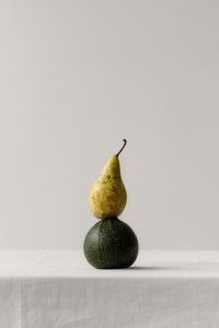 Kaboompics - Pear Balanced on a Dark Green Vegetable, Minimal Still Life Background