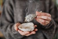 Kaboompics - Close-Up Sage Smudging with a Hand, Smoke and Abalone Shell for Home Cleansing