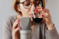 Kaboompics - Woman Sipping Red Wine beside a Microphone in a Cozy ASMR Setup