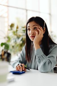 Kaboompics - Thoughtful Asian Woman Using a Calculator at Her Desk