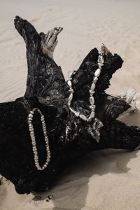 Kaboompics - Silver Necklaces on Black Driftwood by the Sea