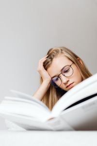 Kaboompics - Teenager Reading Textbook with Hand in Hair