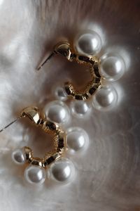 Kaboompics - Macro Close-Up of Pearl Earrings with Gold Detail on Iridescent Shell
