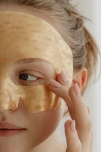 Kaboompics - Close-Up of Woman Adjusting a Beige Facial Sheet Mask Around Her Eye