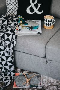 Kaboompics - Coffee Cup and Open Magazines on Gray Sofa with Cozy Throw