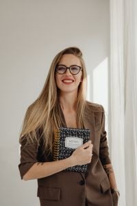 Kaboompics - Smiling Woman Holding Notebook by Window