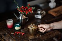 Kaboompics - Hand Holding a Latte in a Rustic Christmas Still Life with Holly and Candles