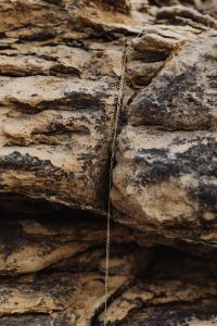 Kaboompics - Delicate Gold Chain Necklace Against Layered Coastal Rock