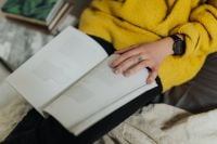 Kaboompics - Overhead View of Open Book on Lap with Hand and Watch, Relaxed Reading Break