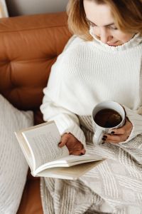 Kaboompics - Woman Reading with Tea on a Cozy Sofa