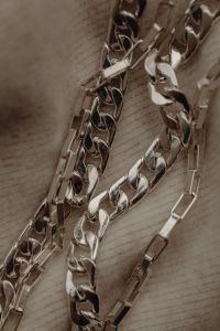 Kaboompics - Chunky and Fine Silver Chains on Gray Fabric