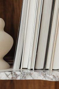 Kaboompics - Close-Up of White Book Spines and a Sculptural Ceramic Vase on Marble