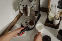 Kaboompics - Hands Holding a Portafilter and Espresso Cup at Coffee Station