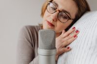 Kaboompics - Woman Resting against a Textured White Pillow beside Microphone, Cozy ASMR