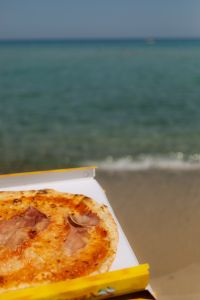 Kaboompics - Takeout Pizza Box on Sand with Sea Background