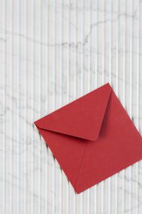 Kaboompics - Vertical Red Envelope on White Marble, Minimal Background with Copy Space