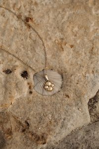 Kaboompics - Gold Necklace with Pearl Charm on Textured Coastal Stone