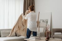 Woman Opening Curtains in a Cozy Living Room