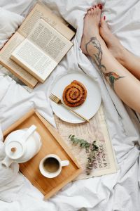 Kaboompics - Relaxing in Bed with a Cinnamon Roll, Coffee and a Book, Tattooed Legs in Frame