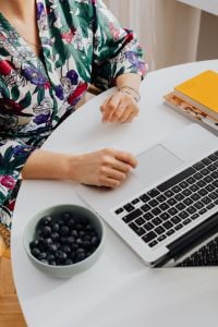 Kaboompics - Woman Using a Laptop Trackpad Beside a Bowl of Blueberries