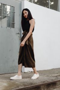 Kaboompics - Side View of Asian Woman in Black Top and Brown Wrap Skirt against White Architecture