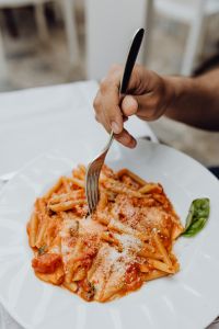 Kaboompics - Hand Eating Tomato Pasta with Parmesan and Fresh Basil